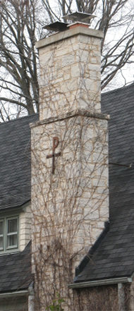 Custom stone chimney on side of house with emblem after waterproofing service